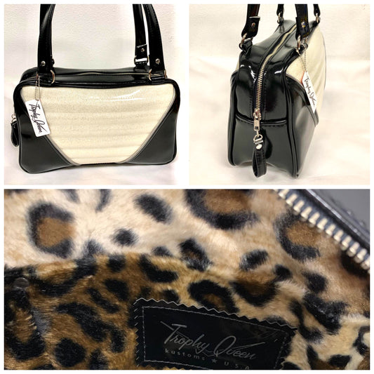 Comet Tote in grease black vinyl and white glitter piping with plush leopard lining handcrafted in California with nickel hardware, an extra set of straps, vinyl zipper pull, inside open divided pocket, zipper pocket with serial number inside and signature Trophy Queen label.