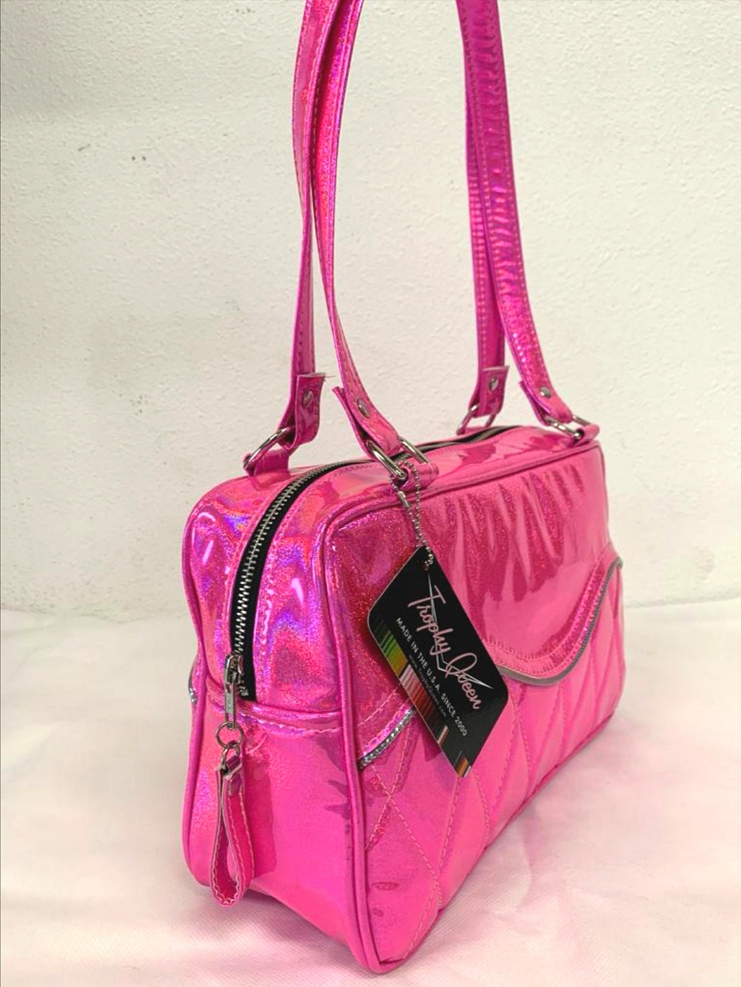 Limited Edition Color the Diamond Pleat Tuck and Roll Tote in Cosmic Pink Glitter Vinyl and plush leopard lining is handcrafted in California with nickel hardware and 25” straps plus it comes with replacement straps. Inside open divided pocket and inside zipper pocket with serial number hidden inside. Nickel feet, vinyl zipper pull, and signature Trophy Queen Label included. The perfect size bag for any trip!