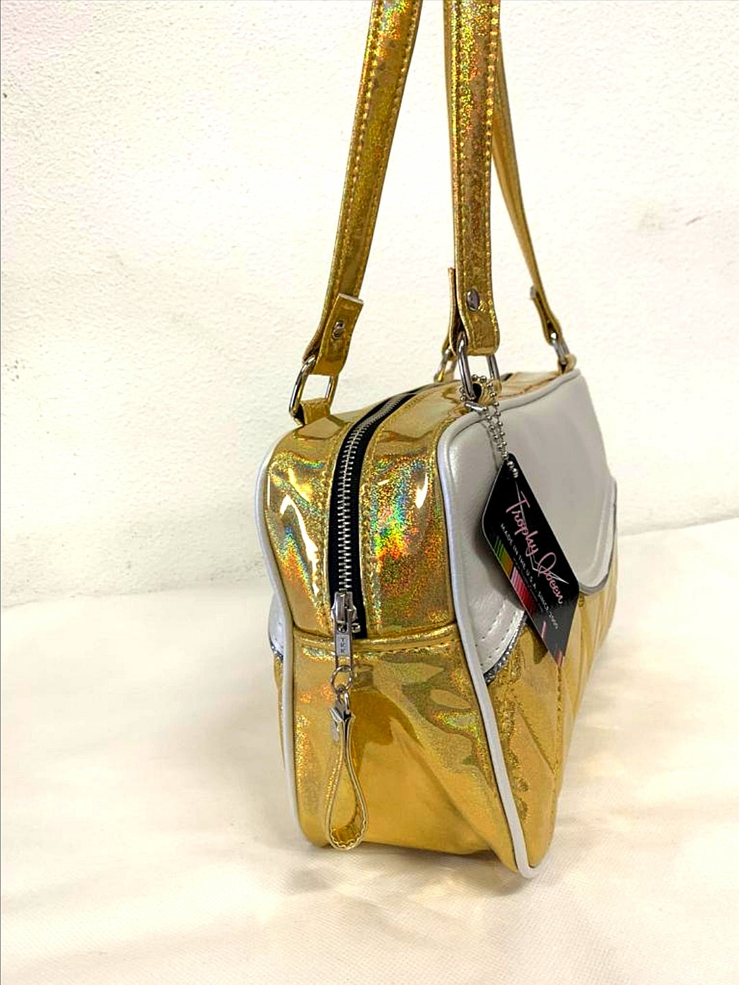 Limited Edition Color the Diamond Pleat Tuck and Roll Tote in Cosmic Gold Glitter and Pearl White Vinyl with plush leopard lining is handcrafted in California with nickel hardware and 25” straps plus it comes with replacement straps. Inside open divided pocket and inside zipper pocket with serial number hidden inside. Nickel feet, vinyl zipper pull, and signature Trophy Queen Label included. The perfect size bag for any trip!
