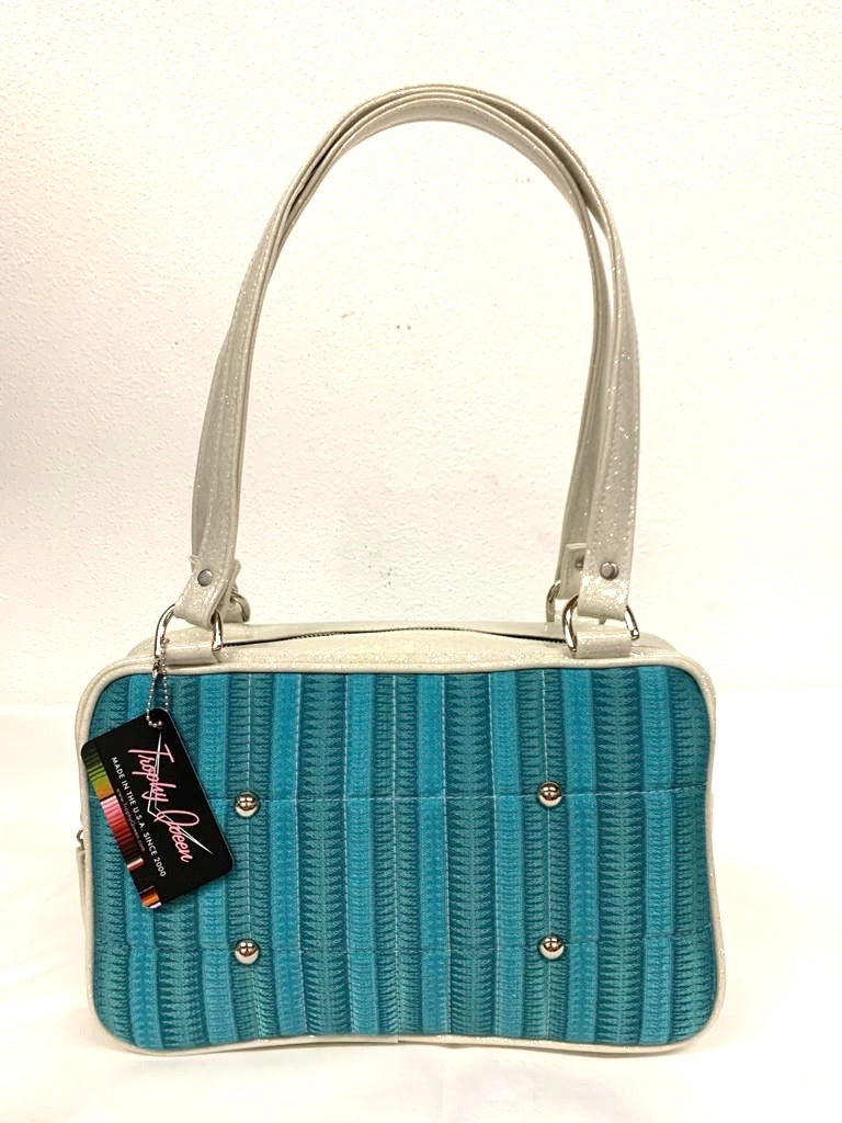 Galaxy Tote, slightly larger than the Galaxy Shoulder Bag in Limited Edition Turquoise ‘65 Chevy Fabric with White Glitter Vinyl and Plush Leopard Lining. Made from NOS Vintage 1965 Chevy Upholstery Fabric with nickel hardware and nickel feet, vinyl zipper pull, and 25” (61cm) straps. Inside you’ll find an open divided pocket, a zipper pocket with serial number inside and signature Trophy Queen Label. Ships from California with an extra set of replacement straps.
