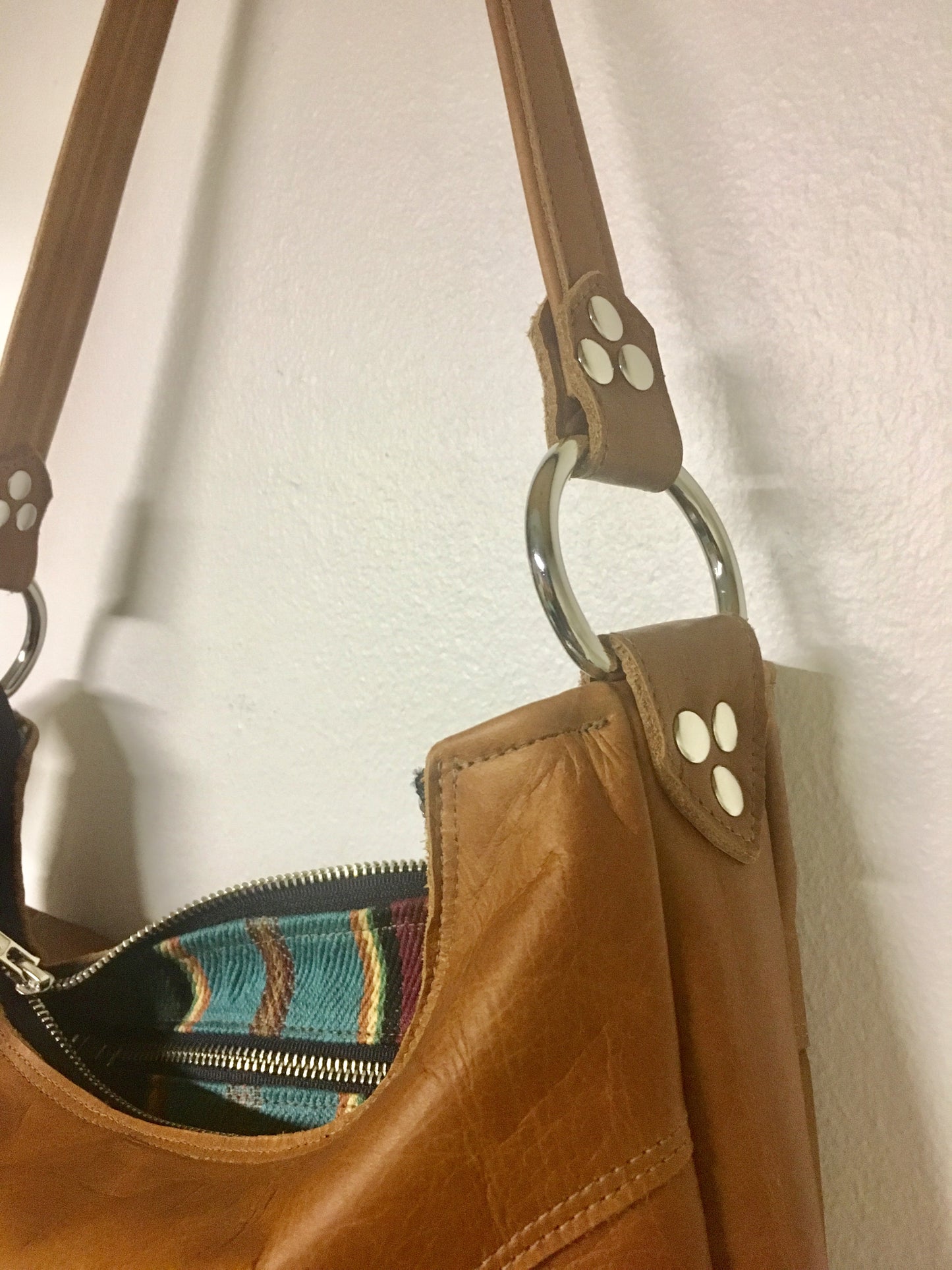 Death Valley hobo shoulder bag in Cognac leather and turquoise serapae print lining with zipper closure and vinyl pull, inside open divided pocket and one zipper pocket with 22” shoulder strap. Signature J.T.Christensen Designs Label inside.