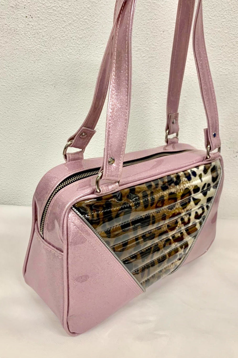 Comet Tote in blush pink glitter vinyl and plush leopard with clear overlay with plush leopard lining handcrafted in California with nickel hardware, an extra set of straps, vinyl zipper pull, inside open divided pocket, zipper pocket with serial number inside and signature Trophy Queen label.