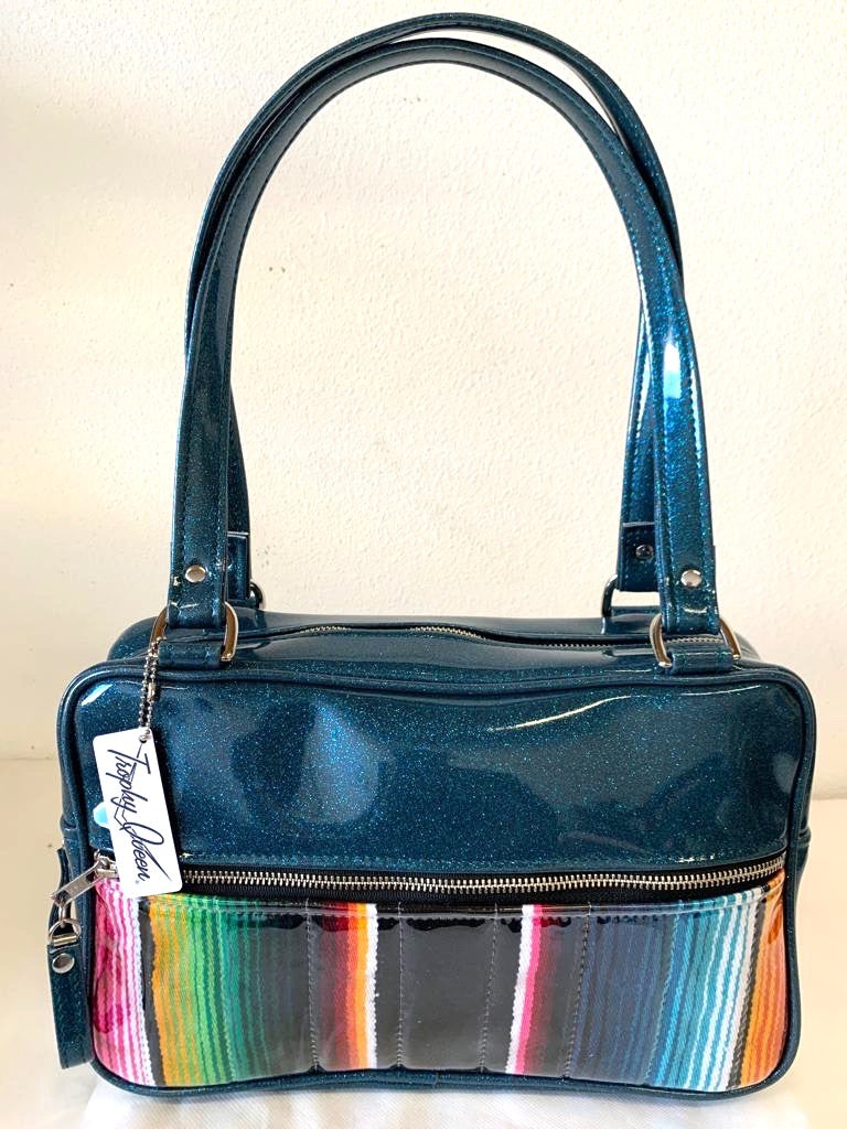 Fairlane Tote Bag in Genuine Mexican Blanket with Clear Overlay and Teal Glitter Vinyl with plush Leopard Lining. This purse has matching vinyl zipper pull, nickel feet, inside zipper pocket with serial number and open divided pocket with signature Trophy Queen label. The straps are approximately 25” and come with an extra set of replacement straps. Locally made and ships from California.