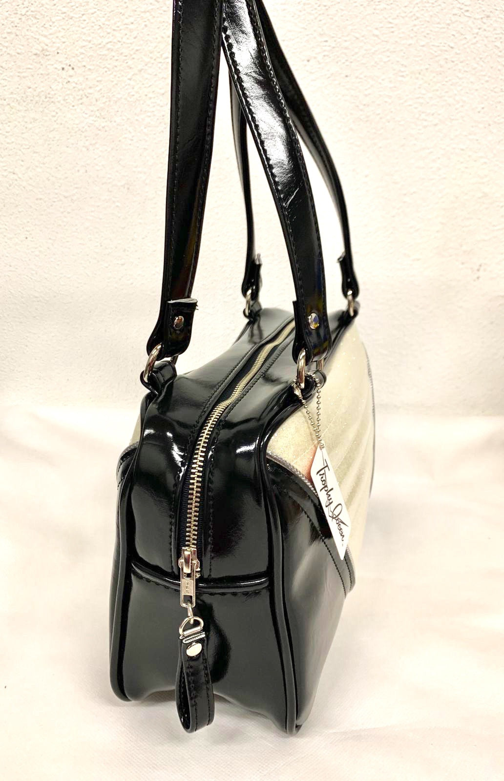 Comet Tote in grease black vinyl and white glitter piping with plush leopard lining handcrafted in California with nickel hardware, an extra set of straps, vinyl zipper pull, inside open divided pocket, zipper pocket with serial number inside and signature Trophy Queen label.