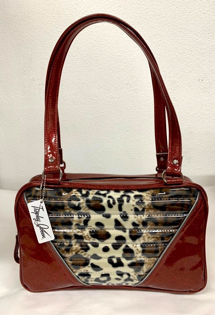 Comet Tote in red glitter vinyl with plush leopard lining handcrafted in California with nickel hardware, an extra set of straps, vinyl zipper pull, inside open divided pocket, zipper pocket with serial number inside and signature Trophy Queen label.