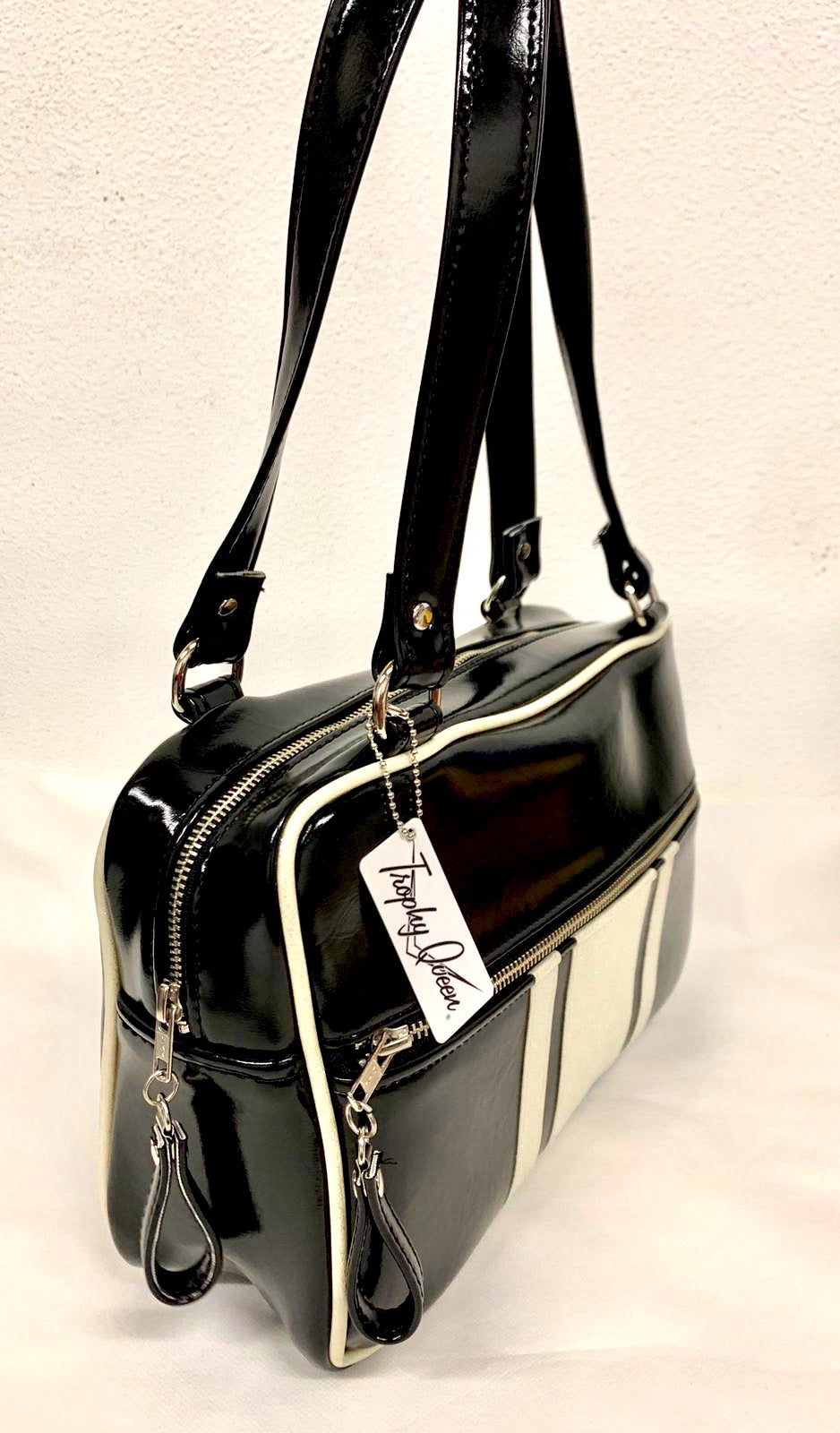 The Galaxy Tote Bag is slightly larger than the Galaxy Shoulder Bag in Grease Black Vinyl and White Glitter Stripes with Plush Leopard Lining. Made with nickel hardware and nickel feet, vinyl zipper pull, and 25” (61cm) straps. Inside you’ll find an open divided pocket, a zipper pocket with serial number inside and signature Trophy Queen Label. Ships from California with an extra set of replacement straps included.