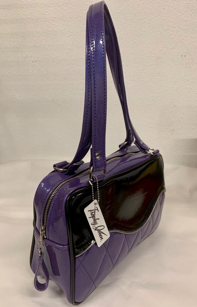 The Diamond Pleat Tuck and Roll Tote in Beatnik Purple Glitter Vinyl and Grease Black with plush leopard lining is handcrafted in California with nickel hardware and 25” straps plus it comes with replacement straps. Inside open divided pocket and inside zipper pocket with serial number hidden inside. Nickel feet, vinyl zipper pull, and signature Trophy Queen Label included. The perfect size bag for any trip!