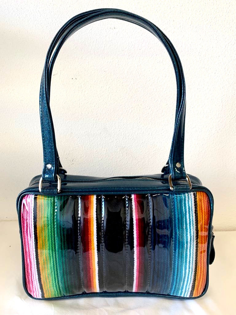 Fairlane Tote Bag in Genuine Mexican Blanket with Clear Overlay and Teal Glitter Vinyl with plush Leopard Lining. This purse has matching vinyl zipper pull, nickel feet, inside zipper pocket with serial number and open divided pocket with signature Trophy Queen label. The straps are approximately 25” and come with an extra set of replacement straps. Locally made and ships from California.