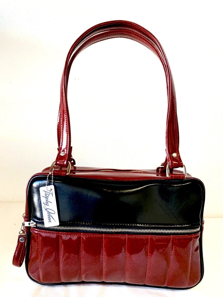 Fairlane Tote Bag in Red Glitter with Grease Black Vinyl with plush Leopard Lining. This purse has matching vinyl zipper pull, nickel feet, inside zipper pocket with serial number and open divided pocket with signature Trophy Queen label. The straps are approximately 25” and come with an extra set of replacement straps. Locally made and ships from California.