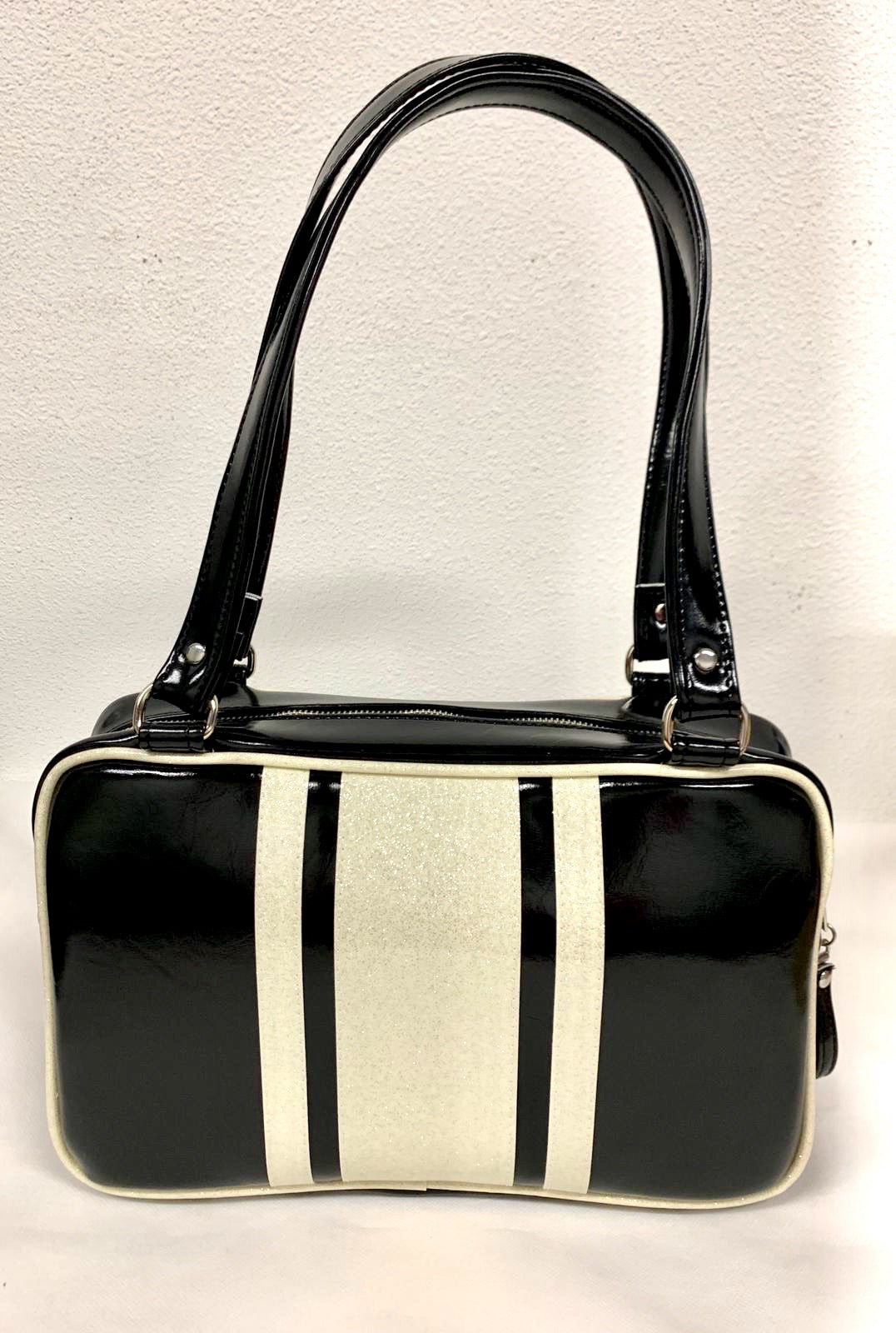The Galaxy Tote Bag is slightly larger than the Galaxy Shoulder Bag in Grease Black Vinyl and White Glitter Stripes with Plush Leopard Lining. Made with nickel hardware and nickel feet, vinyl zipper pull, and 25” (61cm) straps. Inside you’ll find an open divided pocket, a zipper pocket with serial number inside and signature Trophy Queen Label. Ships from California with an extra set of replacement straps included.