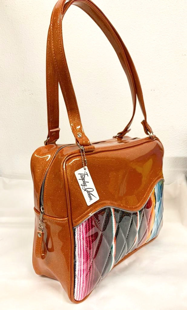 Diamond Pleat Tuck and Roll Business Bag comes in Tangerine Glitter Vinyl and Mexican Blanket with plush leopard lining, 29” straps with nickel hardware and comes with extra replacement straps! Inside has an open divided pocket and zipper pocket with hidden serial number. Tote comes with vinyl zipper pull, nickel fee and signature Trophy Queen label. Made with love in California.
