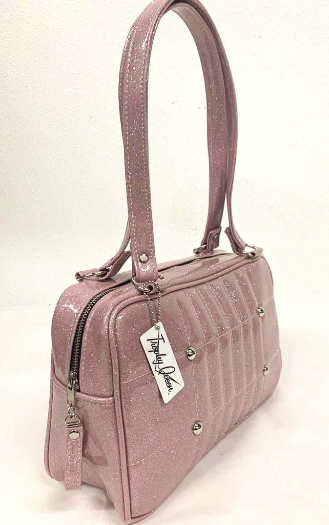 Galaxy Shoulder Bag in Blush Pink Glitter Vinyl and Plush Leopard Lining with nickel hardware and nickel feet, vinyl zipper pull, and 21” (approx 53cm) straps. Inside you’ll find an open divided pocket, a zipper pocket with serial number inside and signature Trophy Queen Label. Ships from California with an extra set of replacement straps.