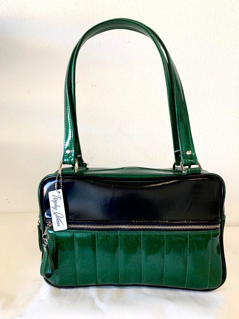 Fairlane Tote Bag in Green Glitter Vinyl and Grease Black Vinyl with plush Leopard Lining. This purse has matching vinyl zipper pull, nickel feet, inside zipper pocket with serial number and open divided pocket with signature Trophy Queen label. The straps are approximately 25” and come with an extra set of replacement straps. Locally made and ships from California.