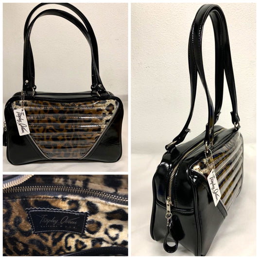 Comet Tote in grease black vinyl and plush leopard with clear overlay with plush leopard lining handcrafted in California with nickel hardware, an extra set of straps, vinyl zipper pull, inside open divided pocket, zipper pocket with serial number inside and signature Trophy Queen label.