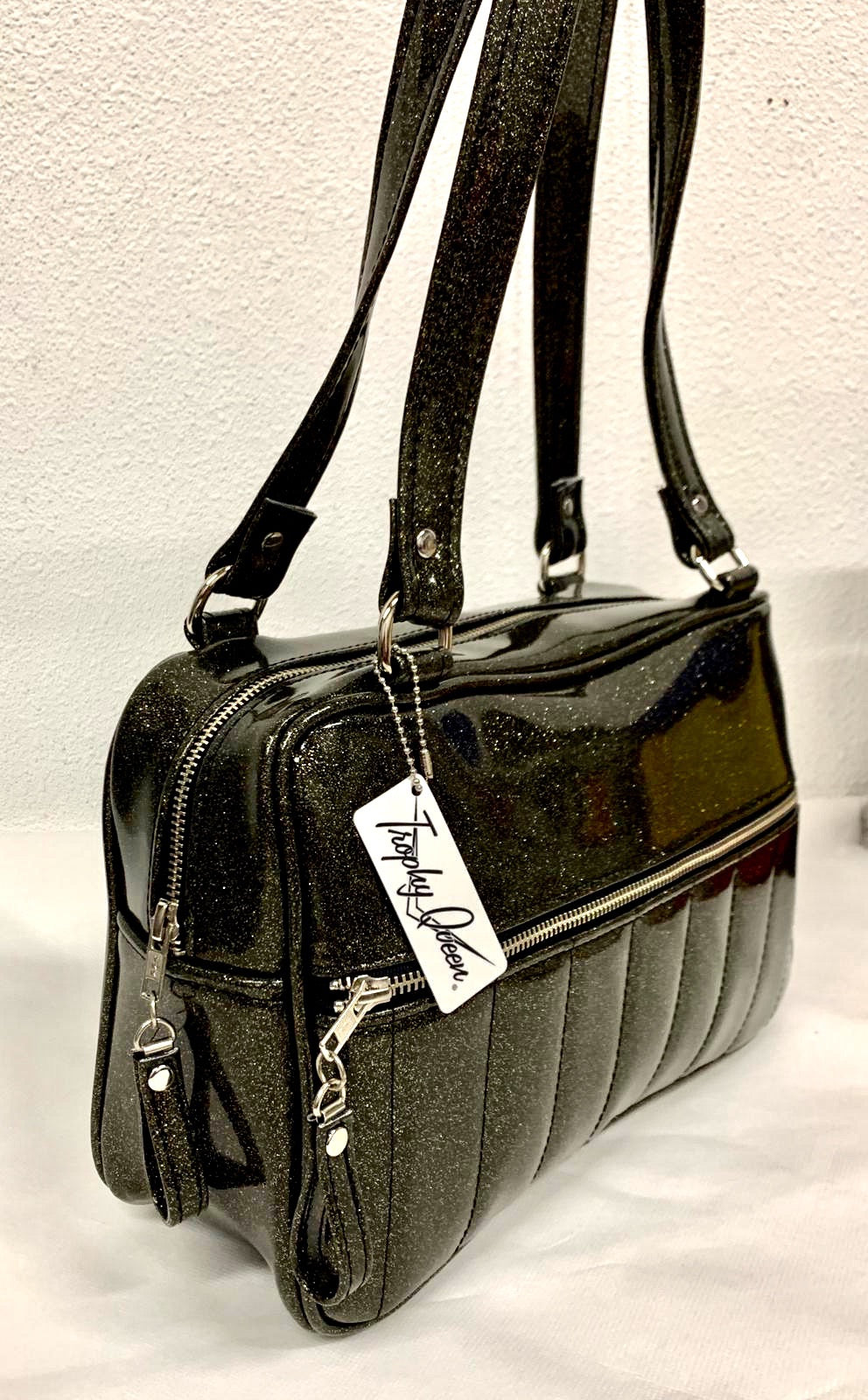 Fairlane Tote Bag in glitter gold speckled black vinyl with plush Leopard Lining. This purse has matching vinyl zipper pull, nickel feet, inside zipper pocket with serial number and open divided pocket with signature Trophy Queen label. The straps are approximately 25” and come with an extra set of replacement straps. Locally made and ships from California.