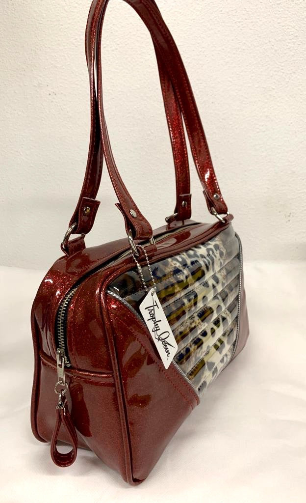 Comet Tote in red glitter vinyl with plush leopard lining handcrafted in California with nickel hardware, an extra set of straps, vinyl zipper pull, inside open divided pocket, zipper pocket with serial number inside and signature Trophy Queen label.