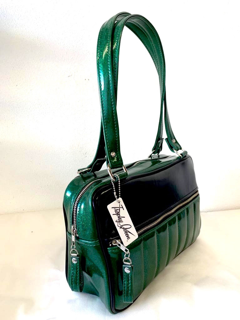 Fairlane Tote Bag in Green Glitter Vinyl and Grease Black Vinyl with plush Leopard Lining. This purse has matching vinyl zipper pull, nickel feet, inside zipper pocket with serial number and open divided pocket with signature Trophy Queen label. The straps are approximately 25” and come with an extra set of replacement straps. Locally made and ships from California.