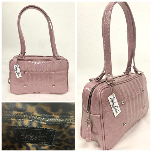 Galaxy Shoulder Bag in Blush Pink Glitter Vinyl and Plush Leopard Lining with nickel hardware and nickel feet, vinyl zipper pull, and 21” (approx 53cm) straps. Inside you’ll find an open divided pocket, a zipper pocket with serial number inside and signature Trophy Queen Label. Ships from California with an extra set of replacement straps.