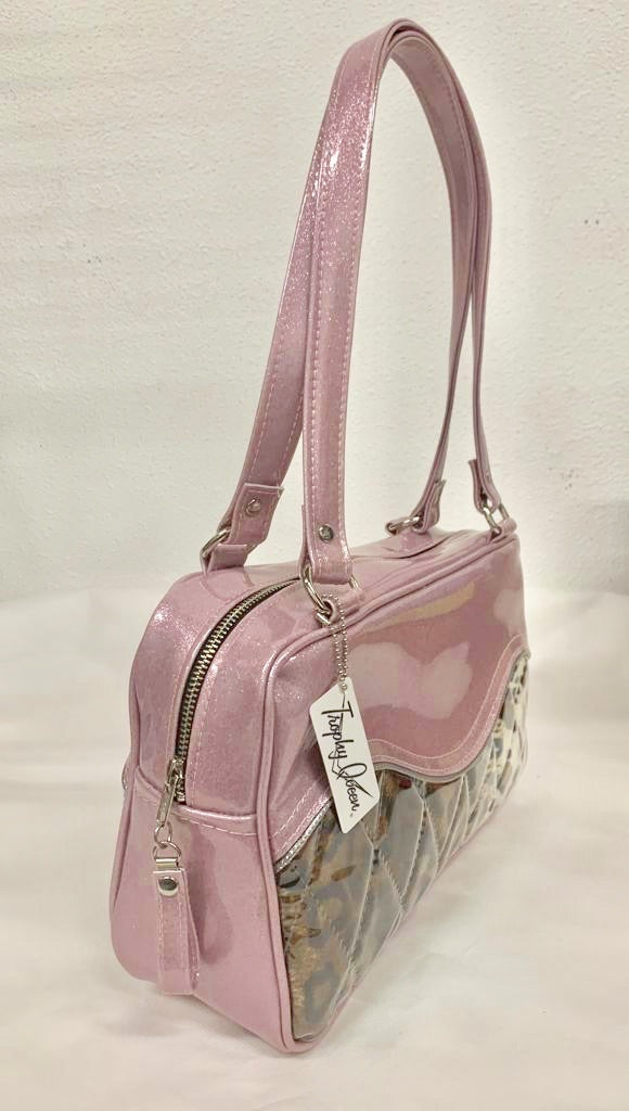 The Diamond Pleat Tuck and Roll Tote in Blush Pink Glitter Vinyl and Leopard with clear overlay lined with matching plush leopard is handcrafted in California with nickel hardware and 25” straps plus it comes with replacement straps. Inside open divided pocket and inside zipper pocket with serial number hidden inside. Nickel feet, vinyl zipper pull, and signature Trophy Queen Label included. The perfect size bag for any trip!